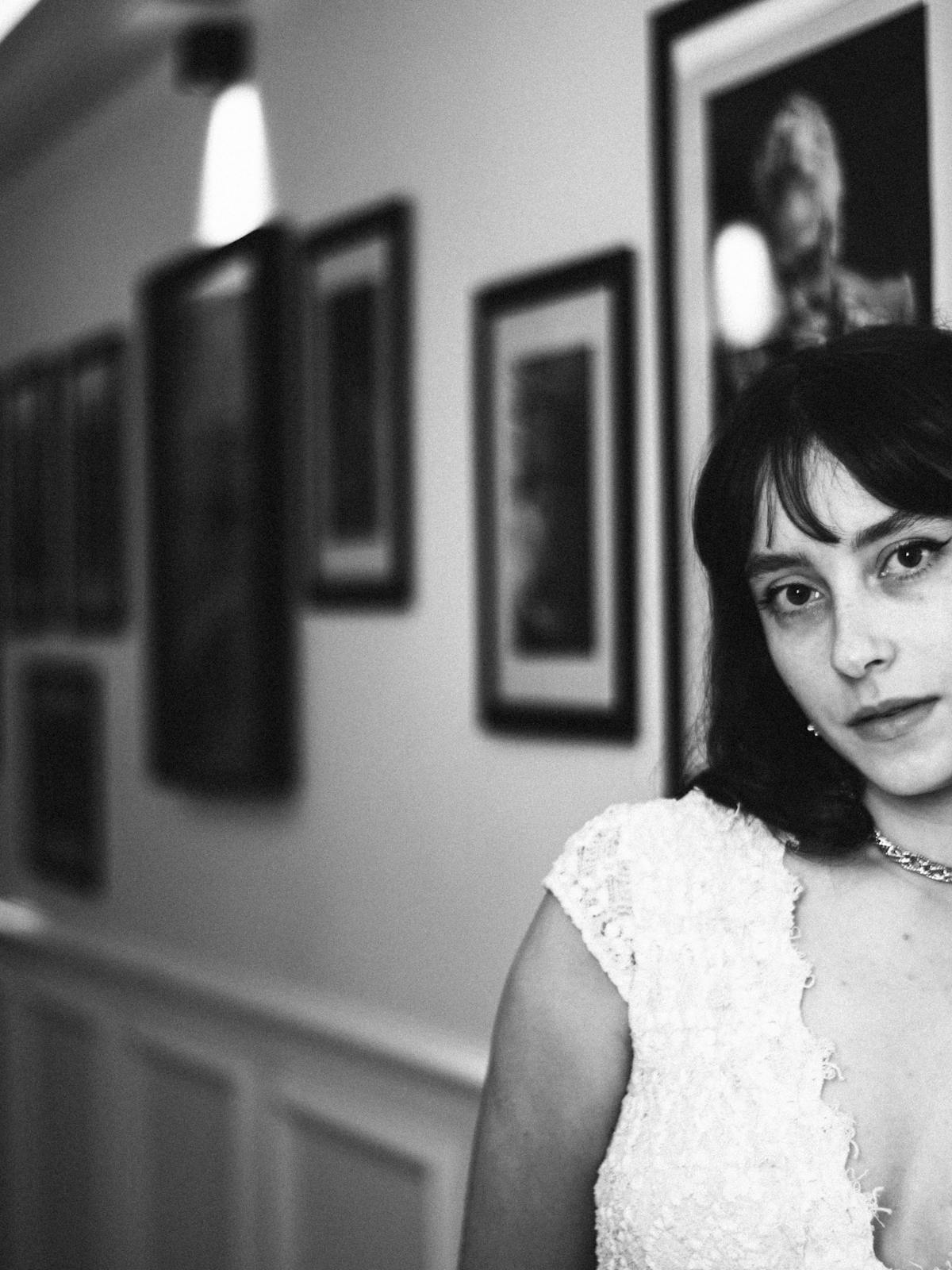 Maya Okonkwo in a Berlin studio, black-and-white portrait against a wall of framed photographs.
