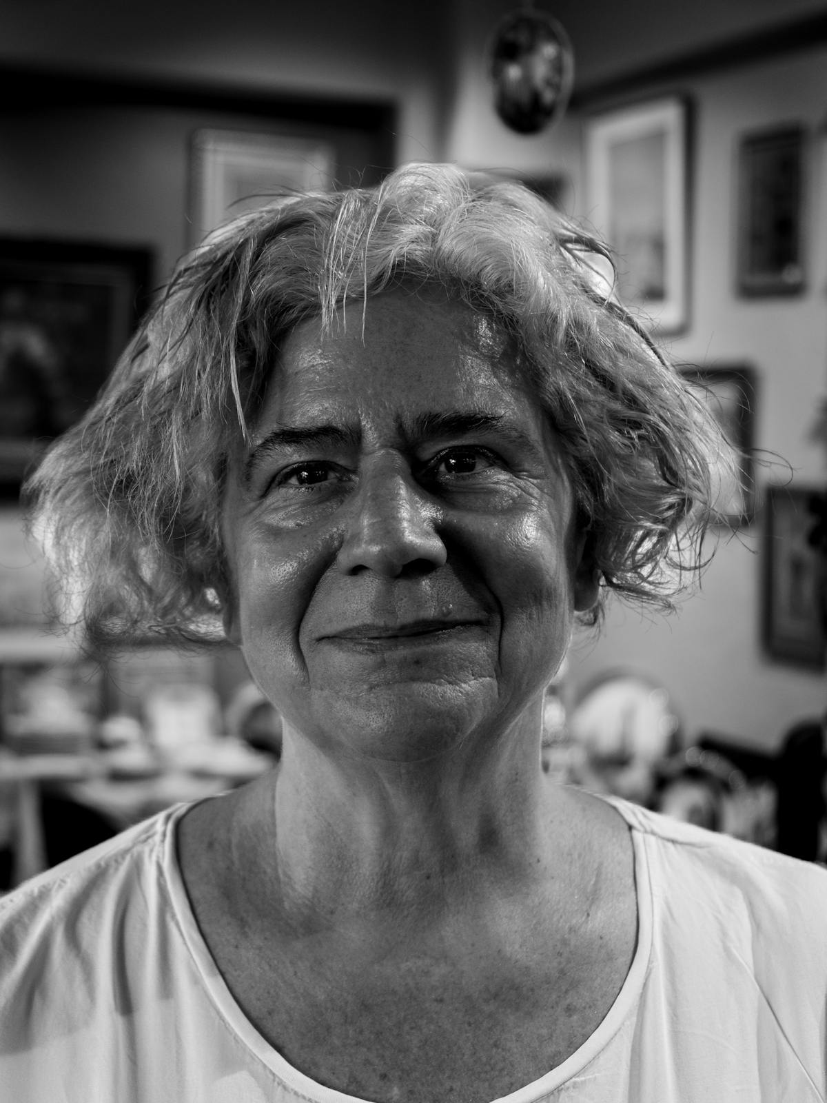 Vera Castellanos in her Brooklyn studio, smiling, paint-flecked apron over a denim shirt.
