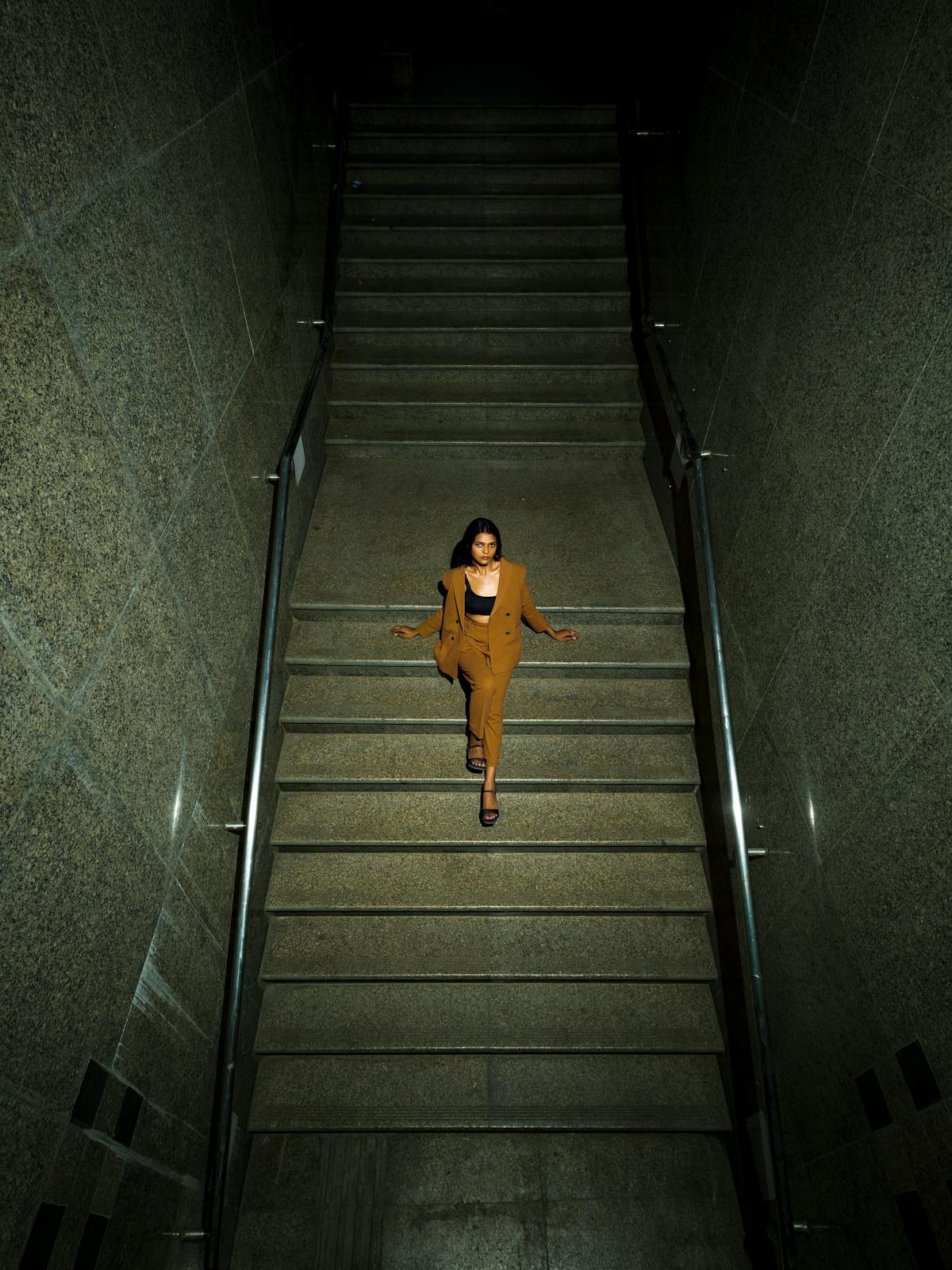 Figure descending a dimly lit staircase.